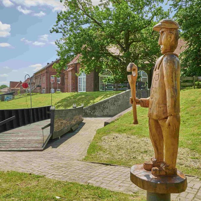 Holzfigur eines Fährmanns mit Großmodel einer Prahmfähre in Oberndorf an der Oste