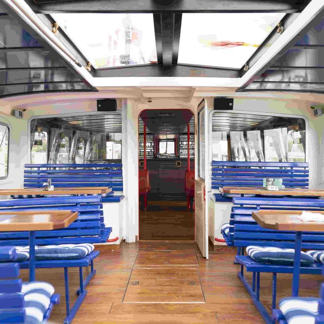 Blick über das teilüberdachte Freideck des Ausflugsschiff Mocambo it blau gestrichenen Bänken und Holztischen