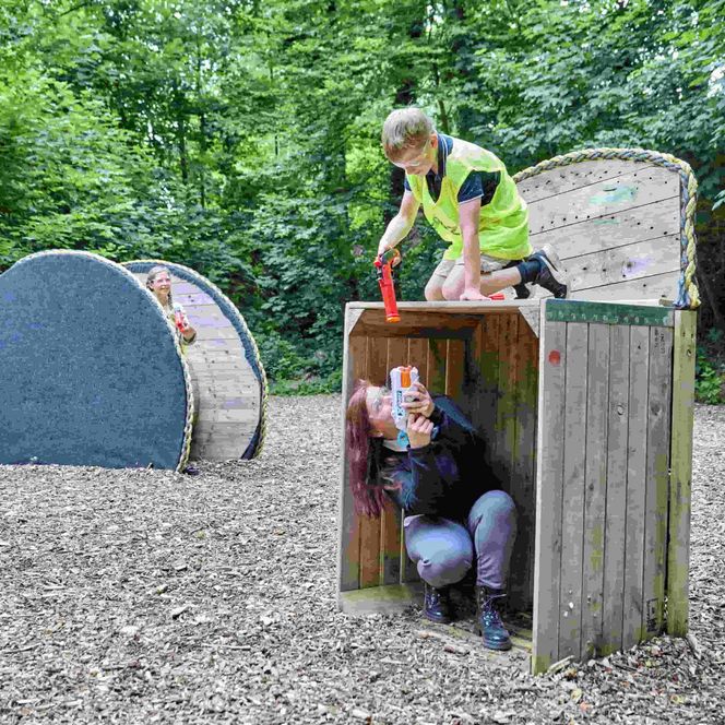 Mutter und Kind überraschen sich gegenseitig in einer Holzbox in der Nerfarena 