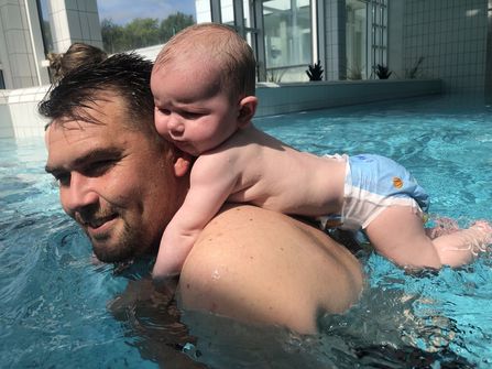 Watsu - Vater mit Baby auf Rücken im Wasser
