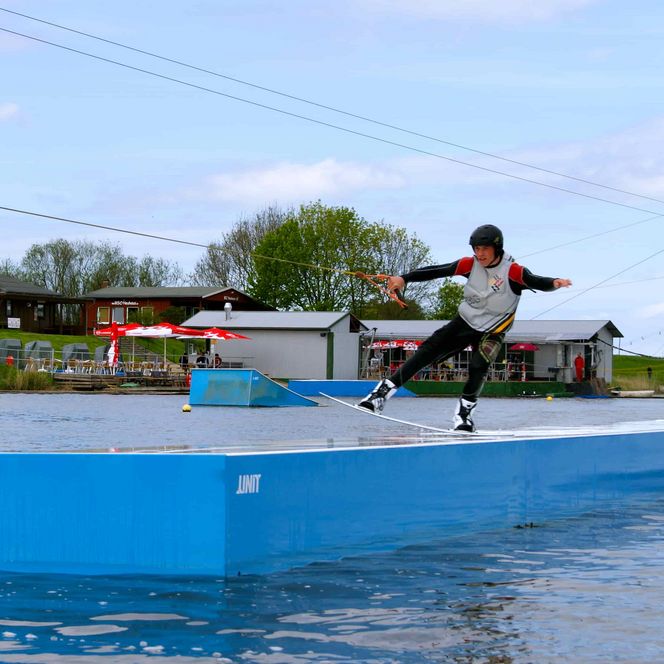 ein Wakeboarder führt einen Stunt auf einen Obstacle auf dem Ostesee durch