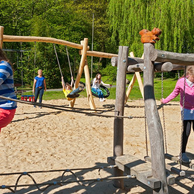 Kinder auf einem Spielplatz im Waldzoo Wingst auf einen Balanciergerüst und im Hintergrund auf einer Schaukel