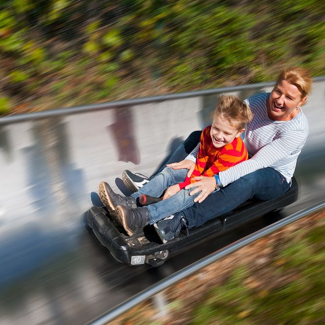 Mutter und Sohn auf der Sommerrodelbahn Wingst auf einem Schlitten