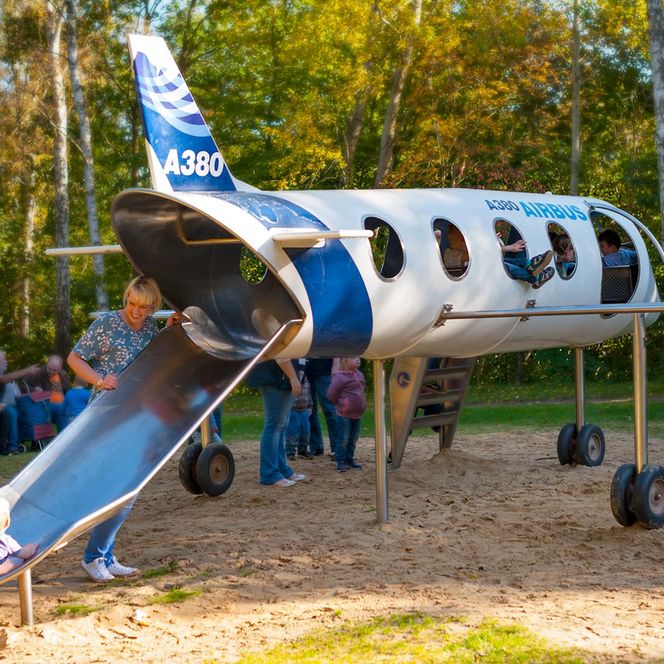 Flugszeugmodel zum Klettern und Rutschen mit Airbuslackierung - EIn Mutter steht an der Heckrutsche und ein Kleinkind schaut die Rutsche hoch