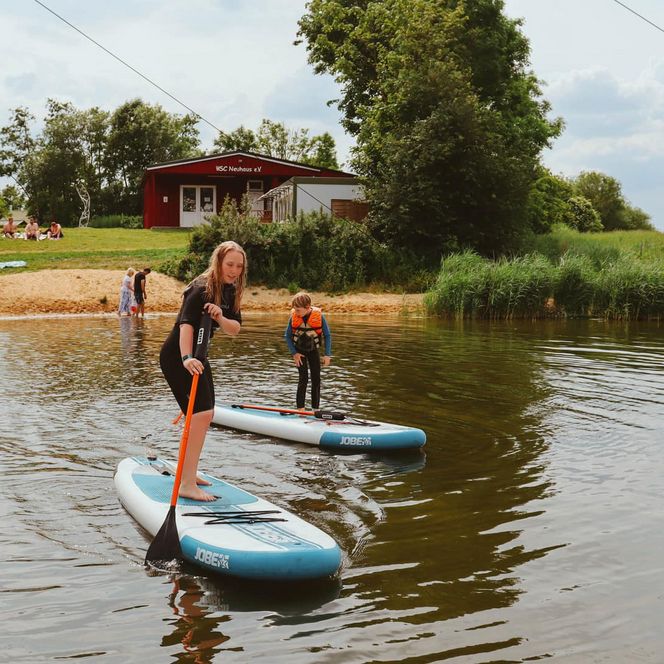 Zwei SUPs auf dem Ostesee, im Hintergrund ein kleiner Sandstrand