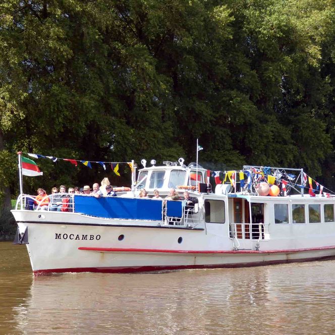 Aussenansicht auf die MS Mocambo von schräg vorne auf der Oste. Im Hintergrund Bäume.