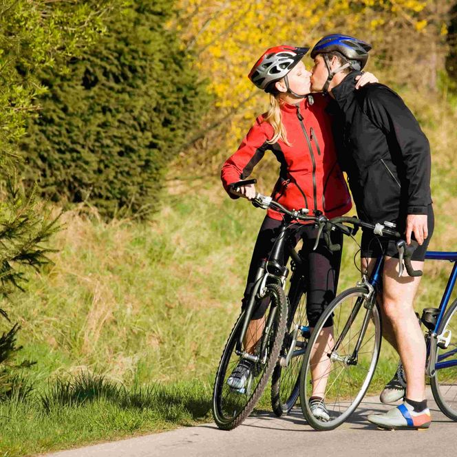 küssendes Paar mit Rennrädern vor herbstlichen Grün