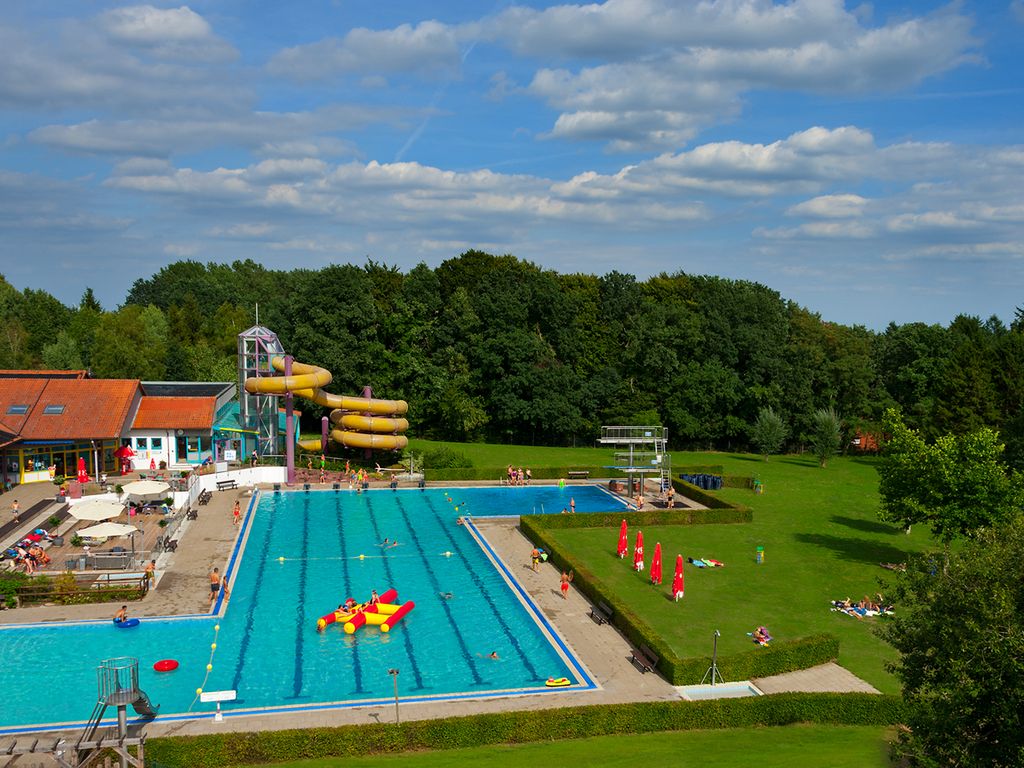 Das Bild zeigt eine Luftaufnahme des Hallen- und Freibades Wingst mit dem großen Schwimmbecken, der Rutsche und dem Außengelände.