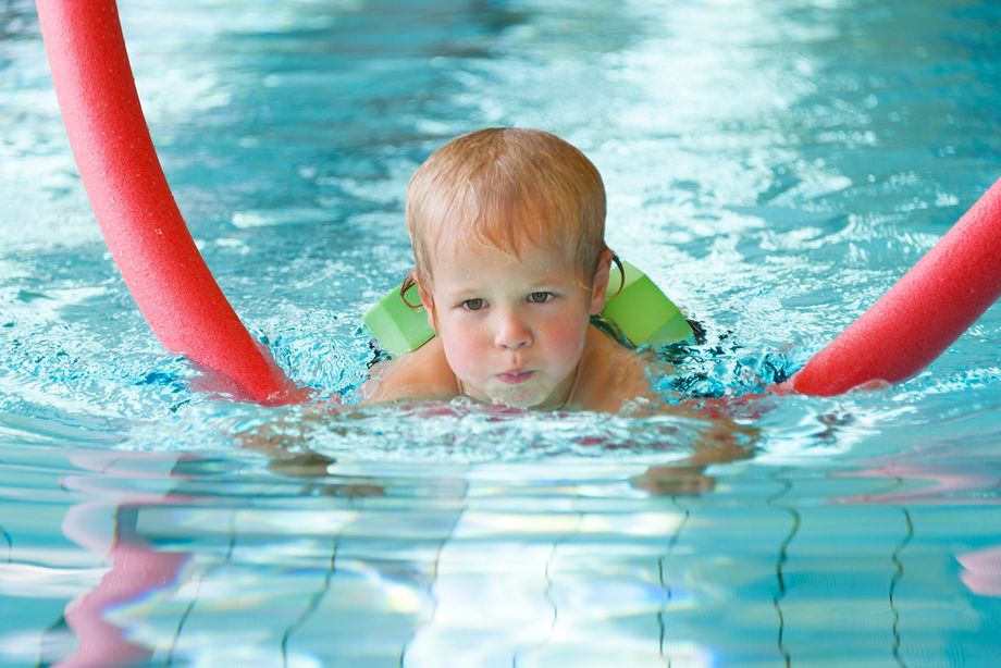 Kind beim Schwimmunterricht mit Schwimmnudel