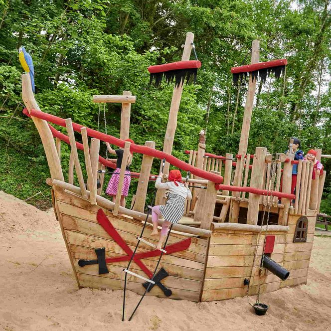 Piratenspielschiff auf Sanduntergrund mit Kindern, die auf dem Schiff klettern