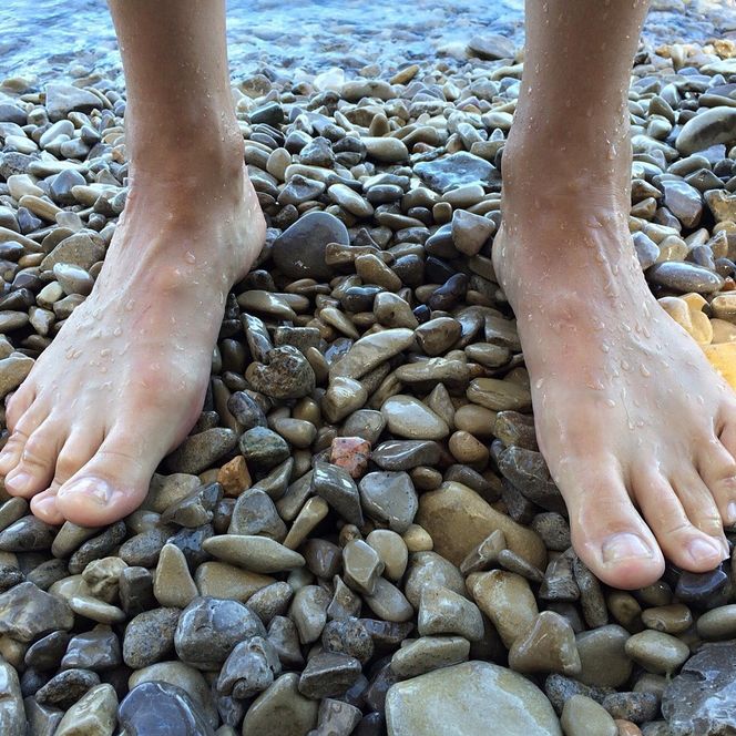 Zwei nackte Füße auf Kieselsteinen 
