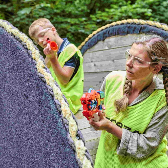 Mutter und Kind suchen Deckung hinter einer alten Kabeltrommel in der Nerf-Arena im Spielpark Wingst